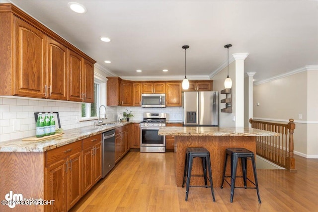 kitchen featuring hanging light fixtures, appliances with stainless steel finishes, sink, and light wood-type flooring