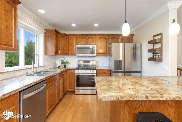 kitchen featuring light stone counters, stainless steel appliances, sink, and hanging light fixtures