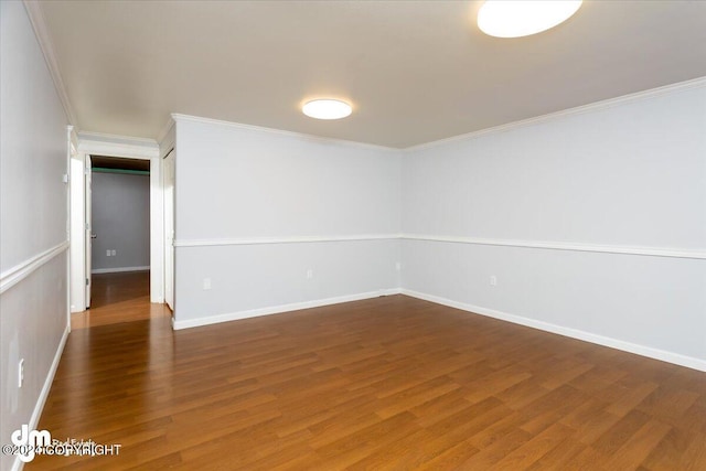 empty room featuring dark wood-type flooring and ornamental molding