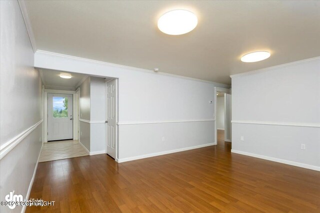 spare room featuring dark wood-type flooring and crown molding