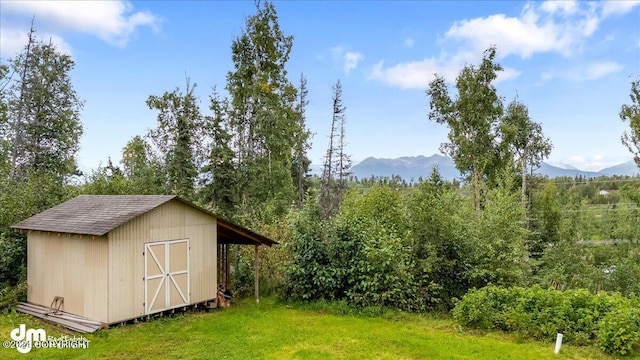 view of outdoor structure with a mountain view and a lawn