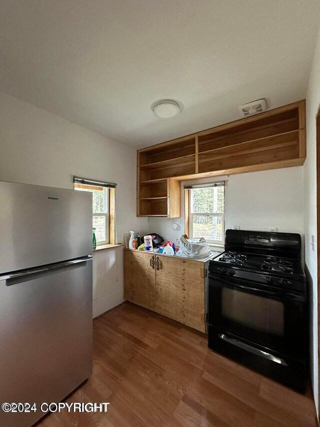 kitchen featuring stainless steel fridge, wood-type flooring, and black gas range oven