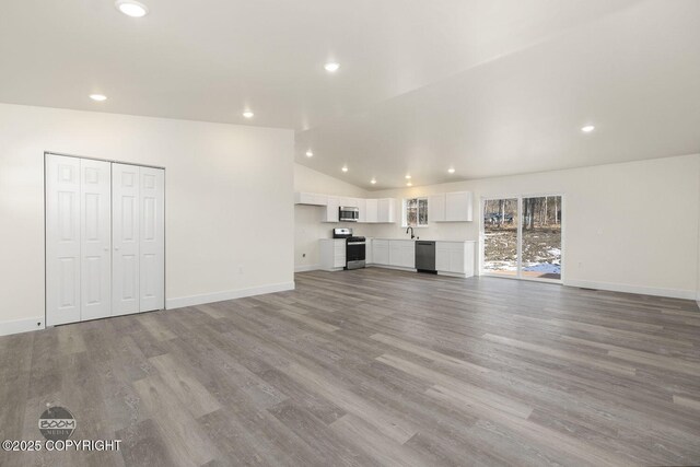 4980 Kelsi Loop, Wasilla, AK 99654 - unfurnished living room featuring recessed lighting, light wood-type flooring, baseboards, and vaulted ceiling
