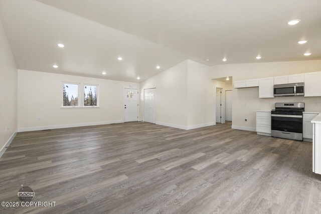 4980 Kelsi Loop, Wasilla, AK 99654 - unfurnished living room featuring vaulted ceiling, recessed lighting, wood finished floors, and baseboards
