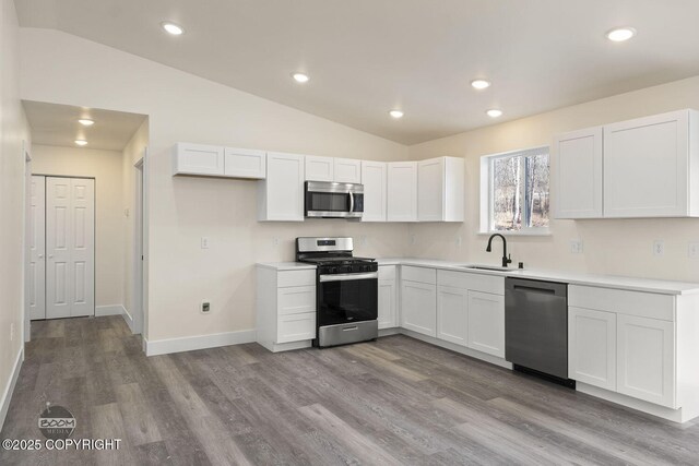 4980 Kelsi Loop, Wasilla, AK 99654 - kitchen featuring vaulted ceiling, white cabinets, appliances with stainless steel finishes, and a sink