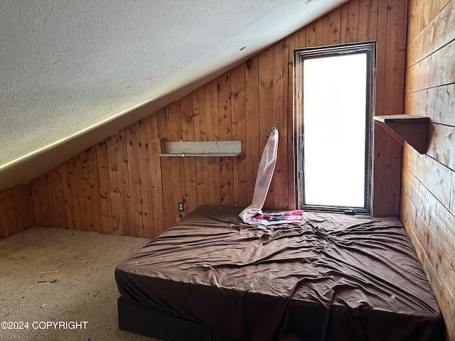 bedroom featuring a textured ceiling, wood walls, carpet, and vaulted ceiling