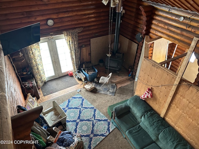 living room featuring a wood stove, french doors, log walls, and lofted ceiling