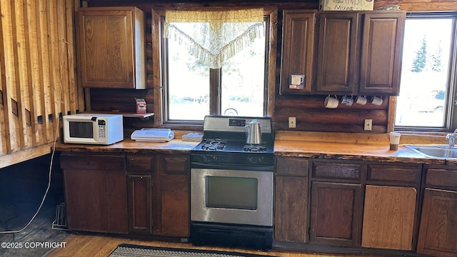 68537 Veater Ave, Ninilchik, AK 99639 - kitchen with white microwave, gas stove, a sink, butcher block counters, and dark brown cabinets