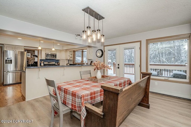 dining space featuring french doors, a textured ceiling, light hardwood / wood-style floors, and sink