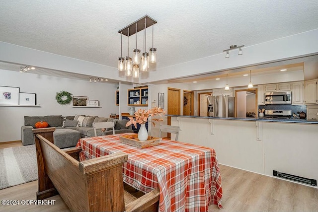 dining area featuring a textured ceiling and light wood-type flooring