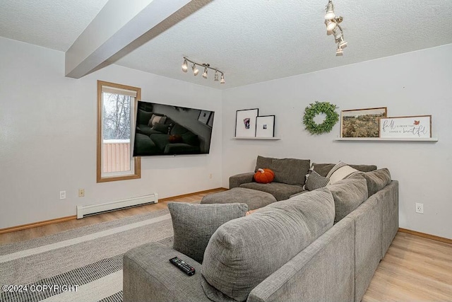 living room with track lighting, a textured ceiling, baseboard heating, beamed ceiling, and light hardwood / wood-style floors