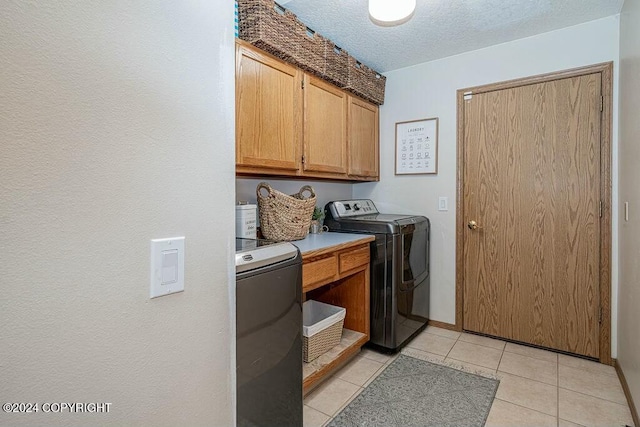 laundry area featuring cabinets, light tile patterned floors, a textured ceiling, and separate washer and dryer