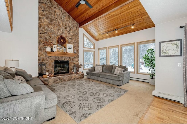 living room featuring baseboard heating, a stone fireplace, a wealth of natural light, and wood ceiling