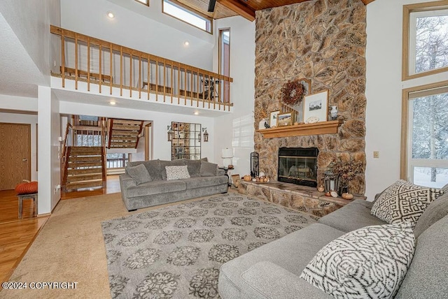 living room featuring beam ceiling, a towering ceiling, a stone fireplace, and a wealth of natural light