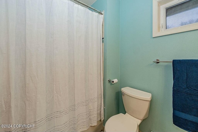 bathroom with a shower with shower curtain and toilet