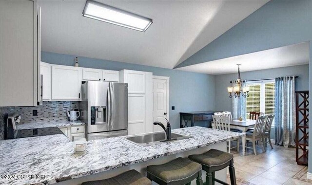 5169 Reliance Rd, Wasilla, AK 99654 - kitchen with stainless steel fridge, stove, lofted ceiling, a chandelier, and a kitchen bar