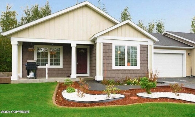 view of front of property with a front lawn, covered porch, and a garage