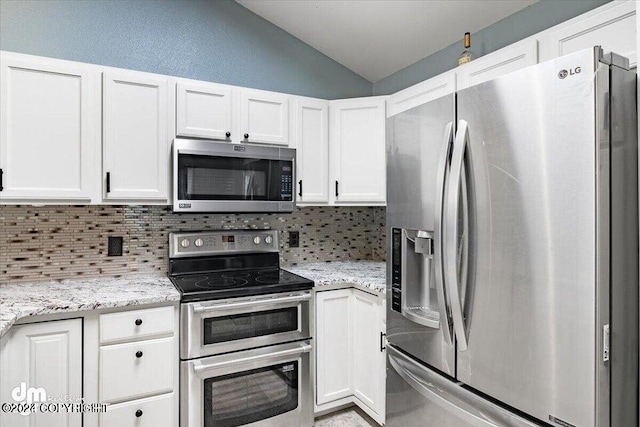 kitchen featuring light stone countertops, stainless steel appliances, white cabinetry, and lofted ceiling