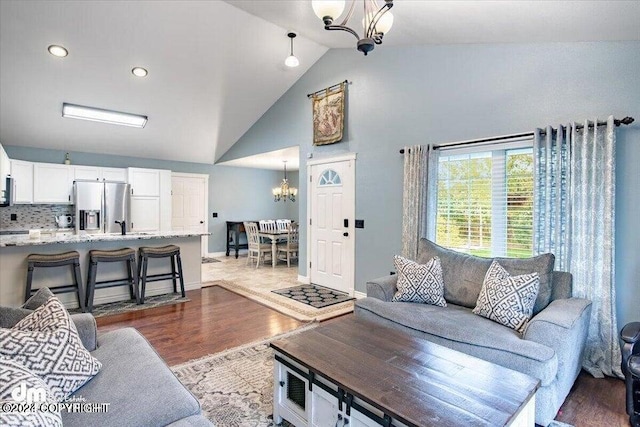 living room featuring hardwood / wood-style floors, high vaulted ceiling, and a notable chandelier