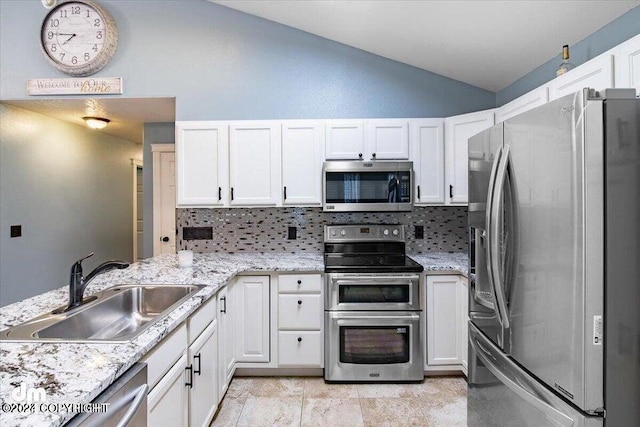 5169 Reliance Rd, Wasilla, AK 99654 - kitchen featuring stainless steel appliances, lofted ceiling, decorative backsplash, white cabinetry, and light stone countertops