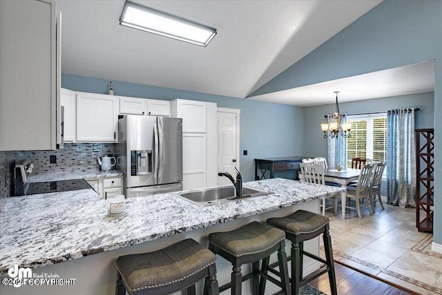 kitchen featuring lofted ceiling, white cabinets, black range, sink, and stainless steel fridge with ice dispenser