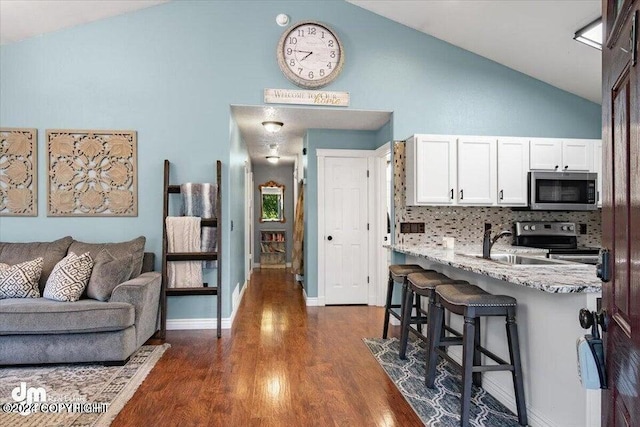 5169 Reliance Rd, Wasilla, AK 99654 - kitchen featuring stainless steel appliances, a breakfast bar, white cabinets, dark wood-style floors, and backsplash