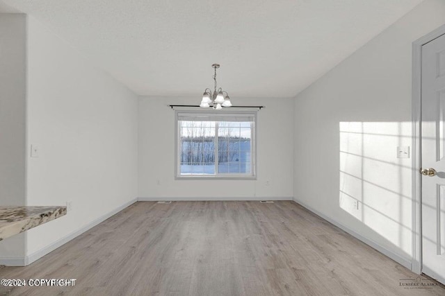 unfurnished dining area with light hardwood / wood-style floors and a chandelier