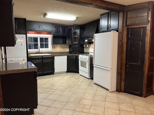 38400 Robinson Loop Rd, Sterling, AK 99672 - kitchen with white appliances, stacked washing machine and dryer, a sink, tasteful backsplash, and dark cabinets