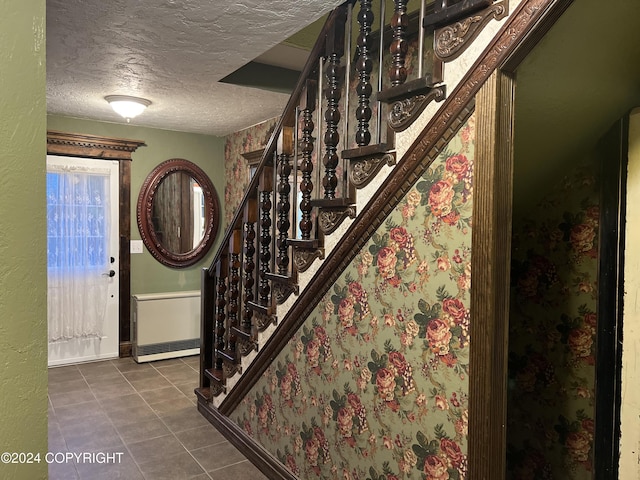 38400 Robinson Loop Rd, Sterling, AK 99672 - entrance foyer featuring a textured ceiling, stairway, dark tile patterned floors, radiator heating unit, and baseboards