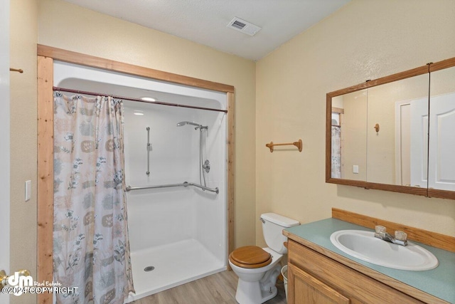 bathroom featuring a shower with shower curtain, wood-type flooring, vanity, and toilet