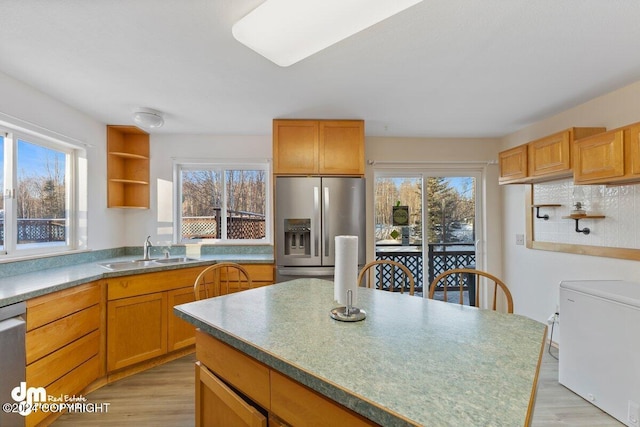 kitchen featuring a wealth of natural light, stainless steel fridge, and sink