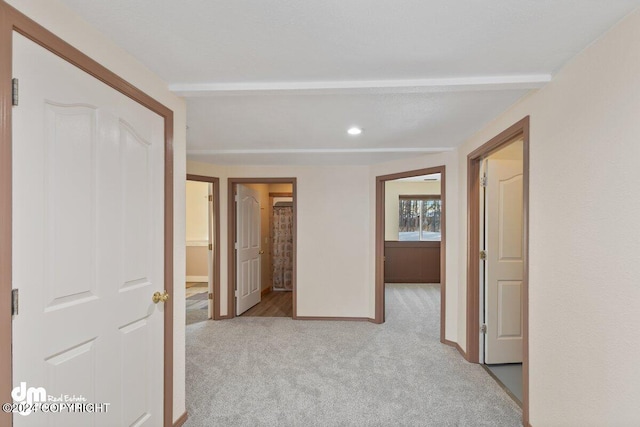 hallway with beam ceiling and light colored carpet