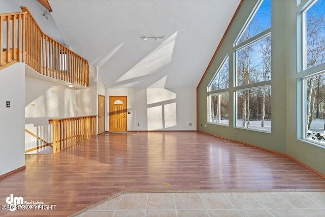 unfurnished living room with wood-type flooring and high vaulted ceiling