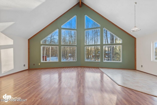 unfurnished living room with hardwood / wood-style flooring and vaulted ceiling with beams