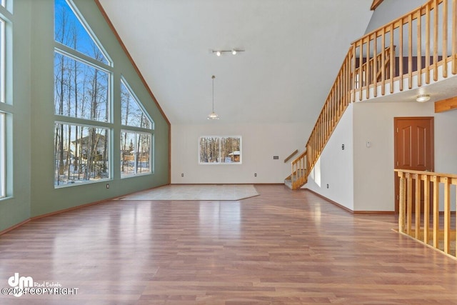 unfurnished living room with a wealth of natural light, high vaulted ceiling, and light hardwood / wood-style flooring