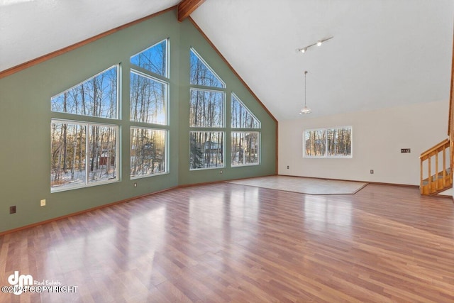 unfurnished living room featuring beam ceiling, light hardwood / wood-style floors, and high vaulted ceiling