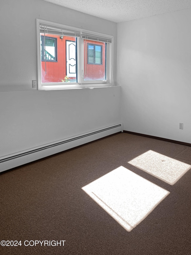 carpeted empty room with a textured ceiling and a baseboard radiator