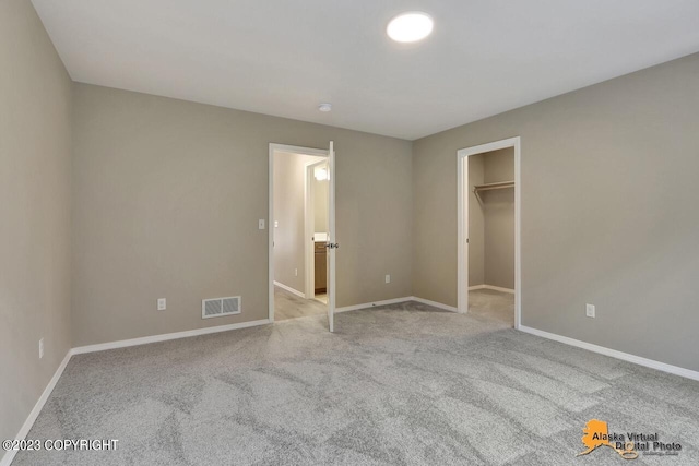 unfurnished bedroom featuring a walk in closet, light carpet, and a closet