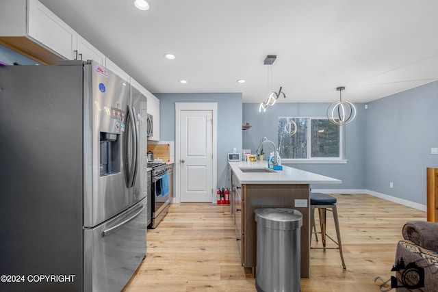 kitchen with sink, stainless steel appliances, decorative light fixtures, a kitchen island with sink, and white cabinets