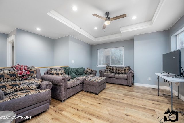 living room featuring plenty of natural light, ceiling fan, light wood-type flooring, and a tray ceiling