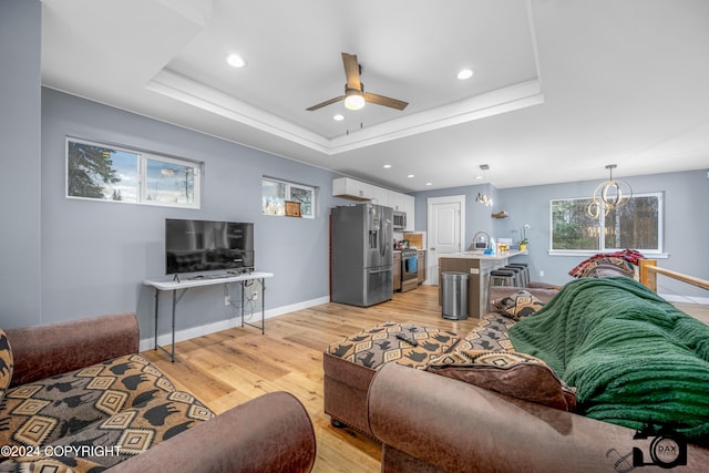 living room featuring a tray ceiling, ceiling fan, sink, and light hardwood / wood-style floors