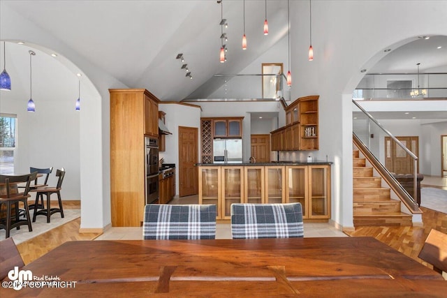 kitchen with hanging light fixtures, high vaulted ceiling, and stainless steel appliances