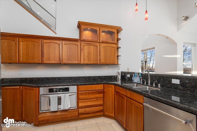 kitchen with appliances with stainless steel finishes, high vaulted ceiling, dark stone countertops, and sink