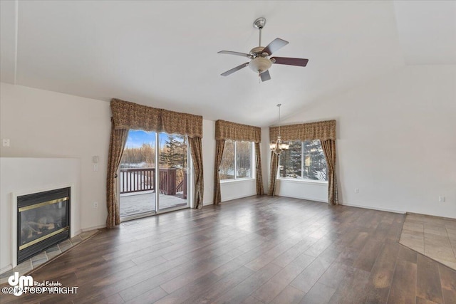 unfurnished living room with dark hardwood / wood-style flooring, a healthy amount of sunlight, and ceiling fan with notable chandelier