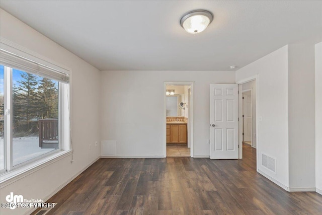 unfurnished bedroom with connected bathroom and dark hardwood / wood-style flooring