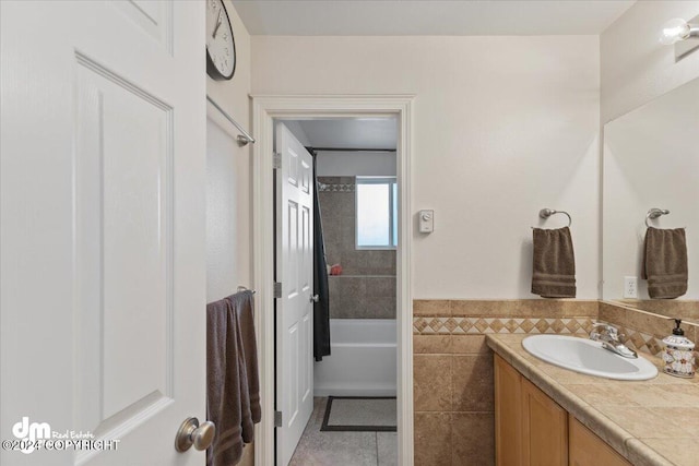 bathroom with tile patterned floors, vanity, a tub to relax in, and tile walls