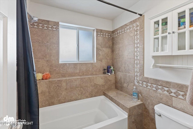 bathroom featuring shower / bath combo, toilet, and tile walls