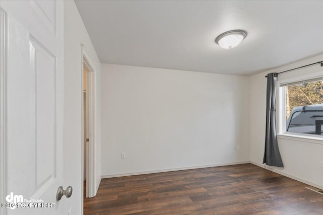 unfurnished room with dark wood-type flooring