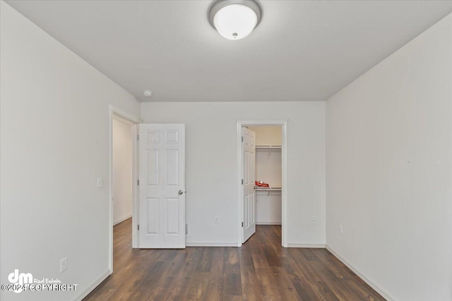 unfurnished bedroom with dark hardwood / wood-style flooring, a spacious closet, and a closet