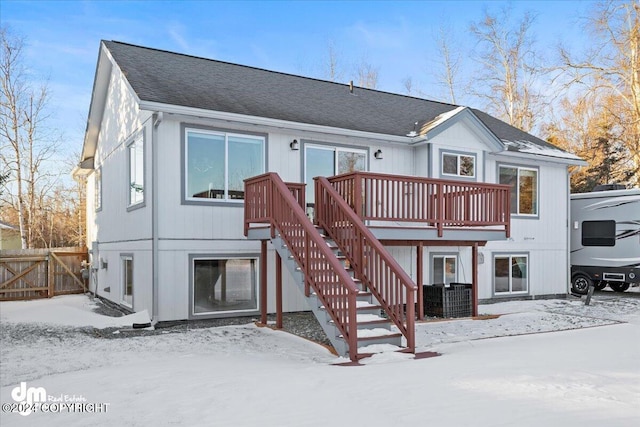 snow covered house with central AC and a wooden deck